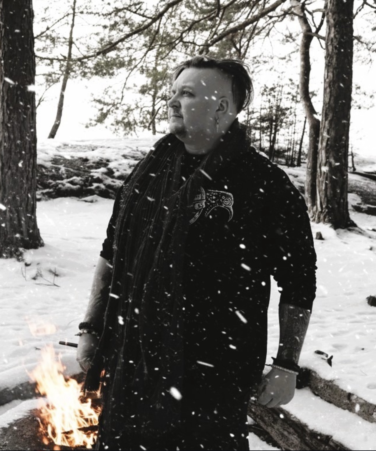 ISVIDD — black and white portrait of the artist standing in a snowy Nordic forest beside a small fire