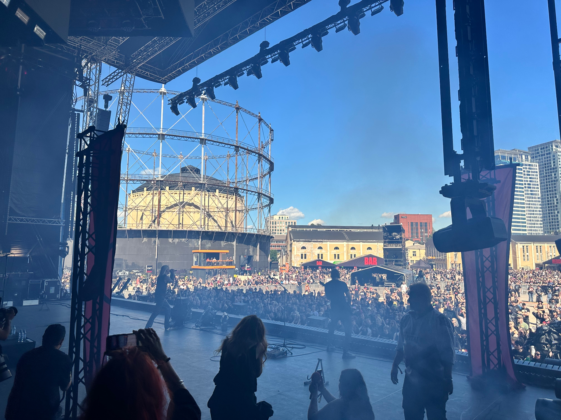 Backstage side-stage view of Hokka performing at Tuska Festival 2026 with the Suvilahti gasometer in the background