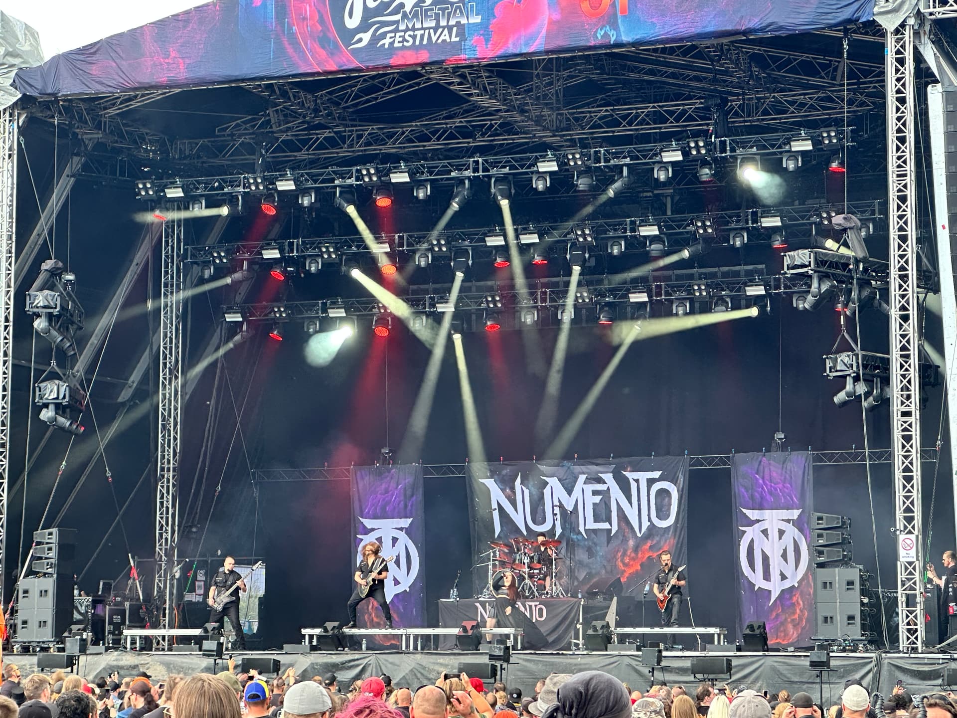 Numento performing at Hellsinki Metal Festival 2026 with banners and a full light show on the outdoor stage
