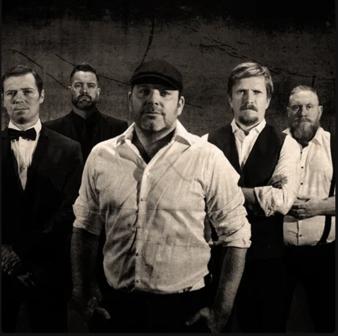Octohawk band photo — five members in dark formal attire against a cracked wall in black and white
